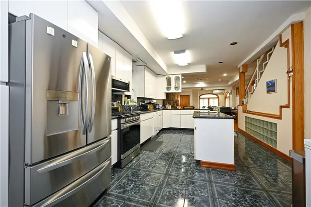 a kitchen with stainless steel appliances granite countertop a refrigerator a oven and white cabinets