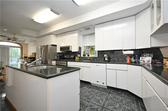 a kitchen with stainless steel appliances granite countertop a sink a stove and white cabinets