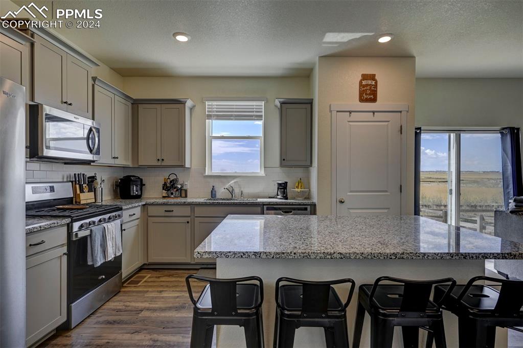 45780 Silverdrop Avenue Bennett, CO 80102 - Photo 14 of 43 a kitchen with granite countertop a stove top oven microwave and cabinets