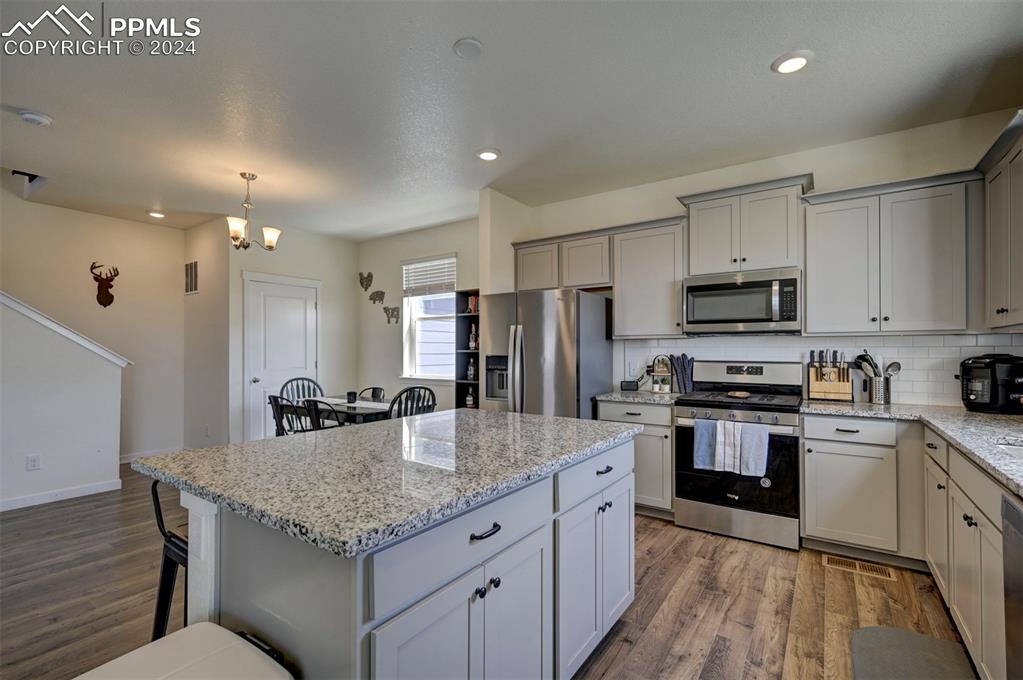 45780 Silverdrop Avenue Bennett, CO 80102 - Photo 16 of 43 a kitchen with stainless steel appliances granite countertop a kitchen island hardwood floor sink and stove