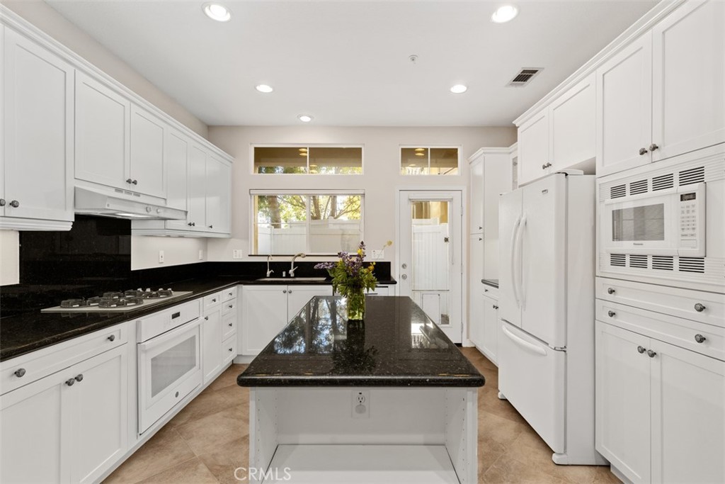 a kitchen with granite countertop a sink stainless steel appliances and cabinets