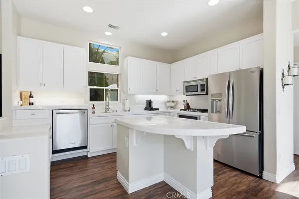 a kitchen with a sink a stove a refrigerator and white cabinets