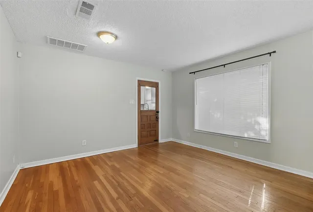 an empty room with wooden floor and windows