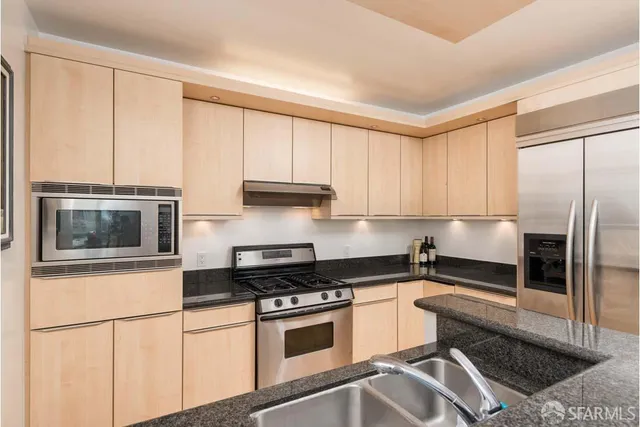 a kitchen with stainless steel appliances granite countertop a stove a sink and a refrigerator