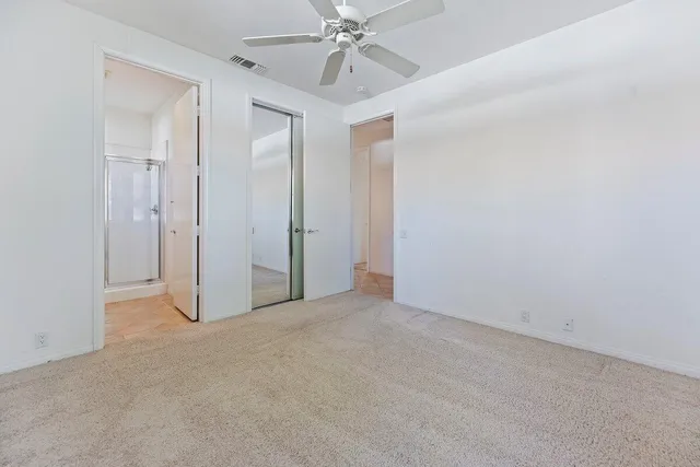 an empty room with a chandelier fan and closet area