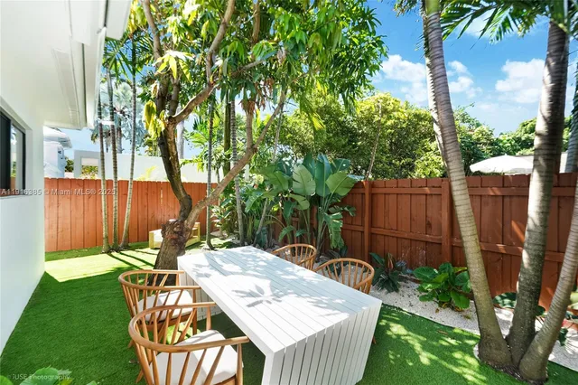 a view of a backyard with table and chairs potted plants and wooden fence