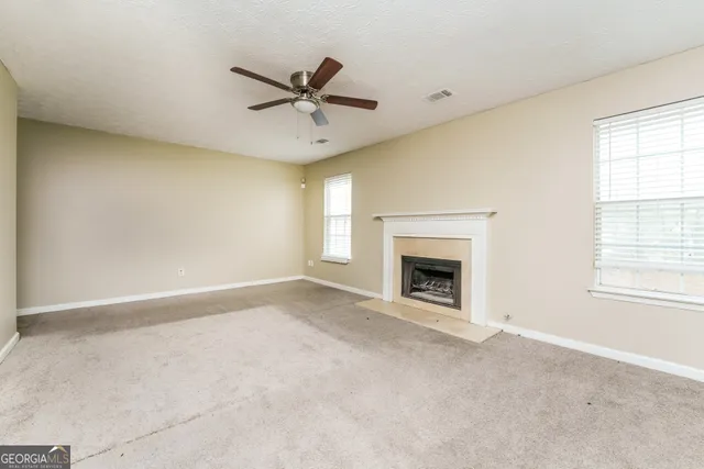 a view of an empty room with a window and fireplace
