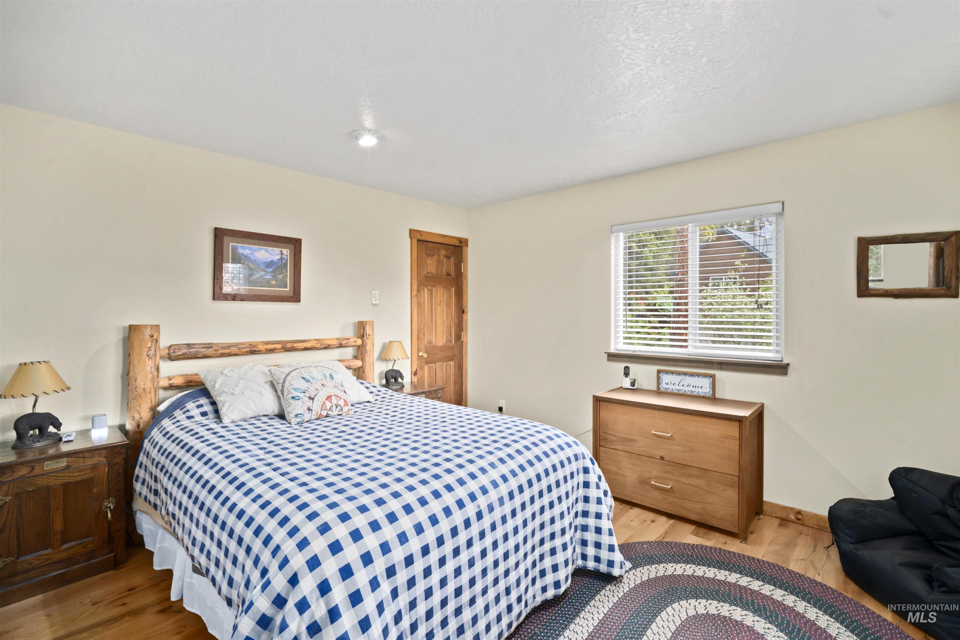9 Deer Valley Road Garden Valley, ID 83622 - Photo 12 of 22 Bedroom featuring wood-finish flooring, a wood-frame window with blinds, and a solid wood door