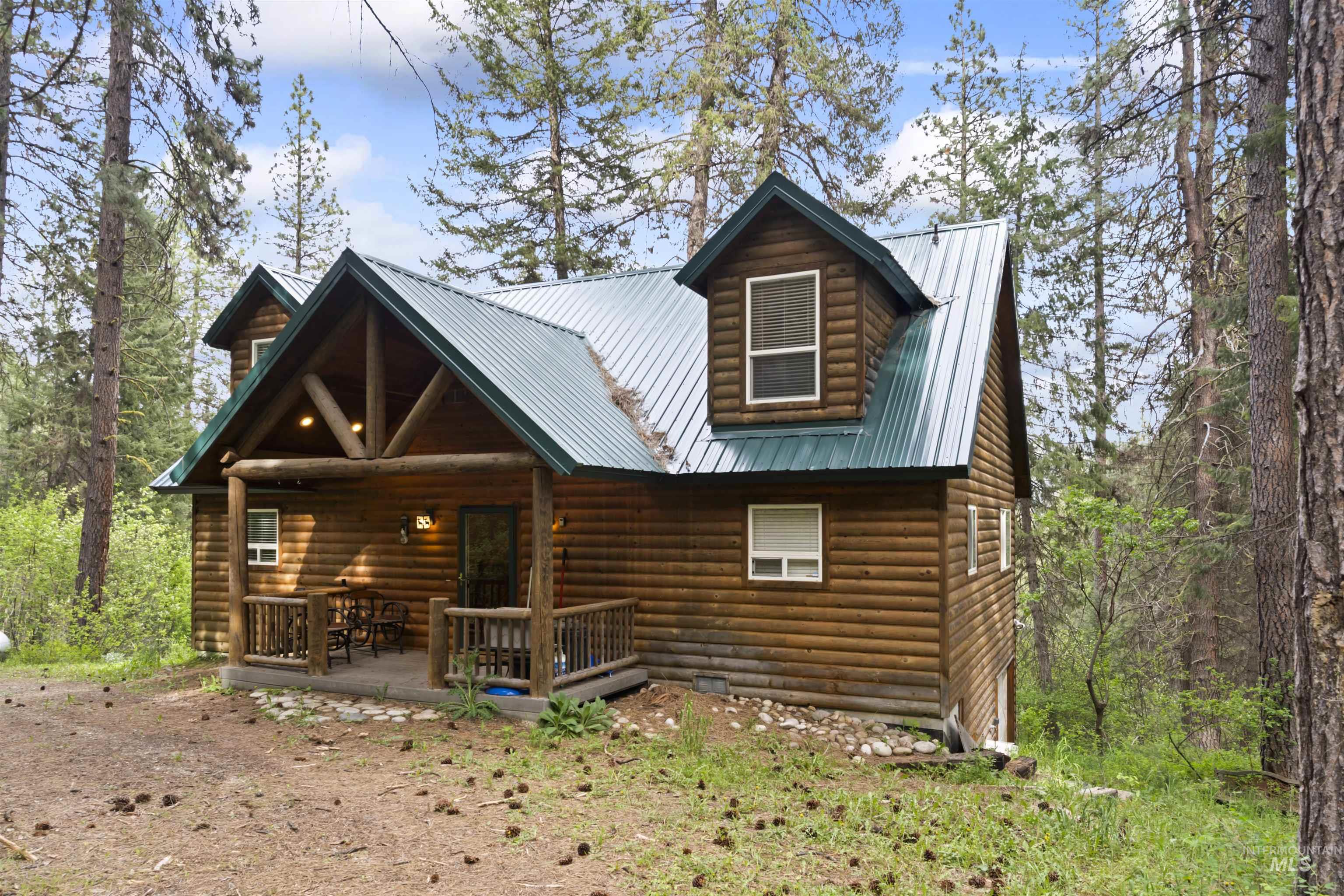 9 Deer Valley Road Garden Valley, ID 83622 - Photo 3 of 22 Log cabin exterior featuring a covered porch, green metal roof, dormer windows, and natural wood siding