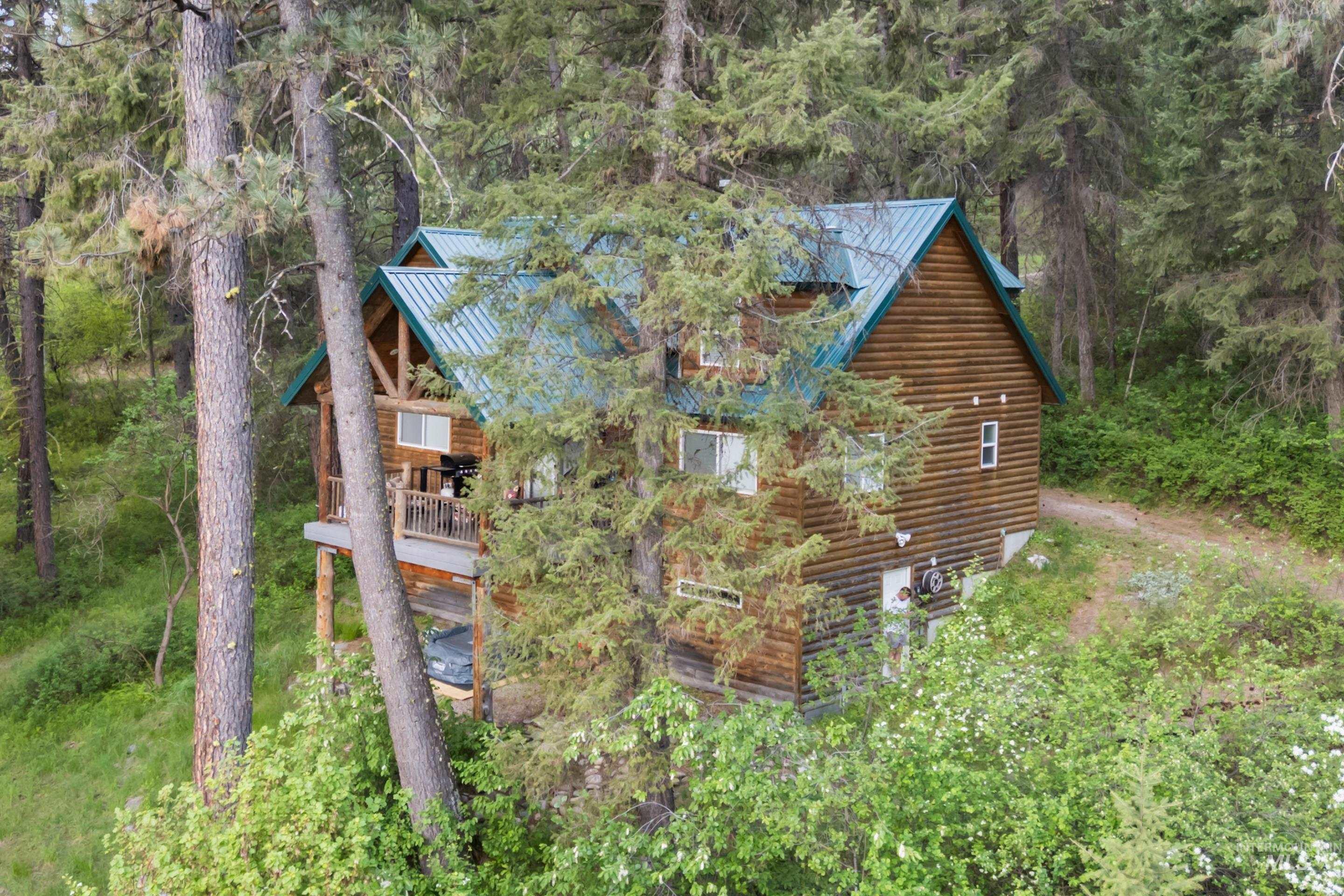 9 Deer Valley Road Garden Valley, ID 83622 - Photo 6 of 22 Log cabin style home featuring a metal roof, wood siding, multiple windows, and an upper-level balcony