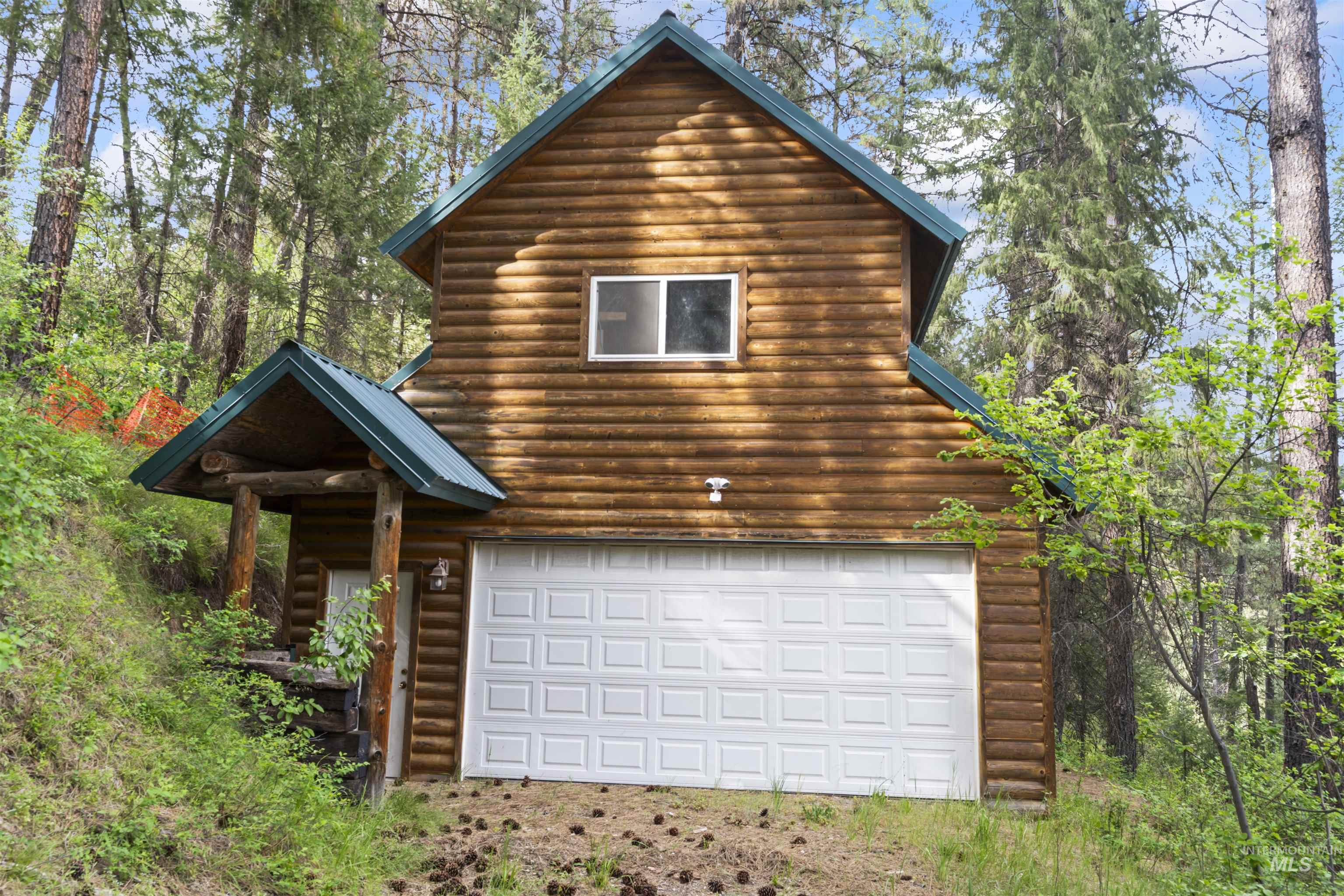 9 Deer Valley Road Garden Valley, ID 83622 - Photo 7 of 22 Wood-sided structure featuring a prominent garage door, an upper-level window, and a covered entry with log supports