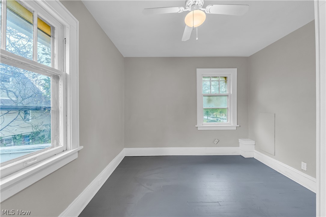 1144 East 145th Street, Unit 1/RIGHT Cleveland, OH 44110 - Photo 13 of 20 Room featuring painted wood-finish flooring, two large windows with white trim, a ceiling fan with integrated lighting, and neutral wall tones