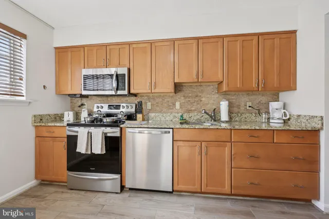 a kitchen with stainless steel appliances granite countertop a stove a sink dishwasher and a refrigerator