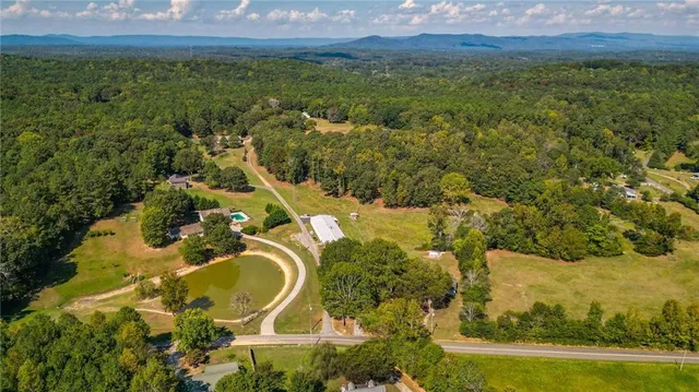 an aerial view of residential house with outdoor space and trees all around