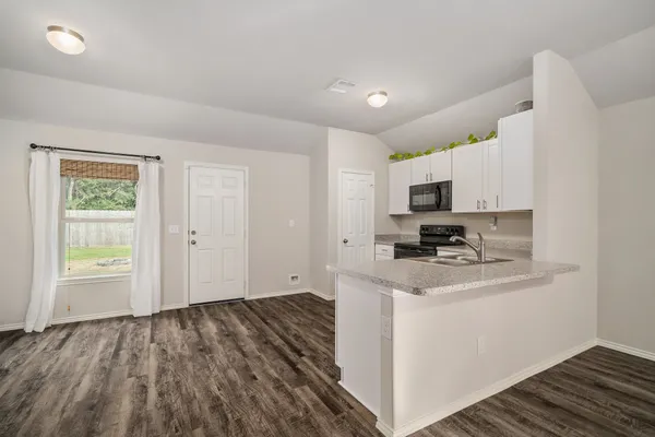 a kitchen with granite countertop a stove top oven a sink dishwasher and a refrigerator with wooden floor
