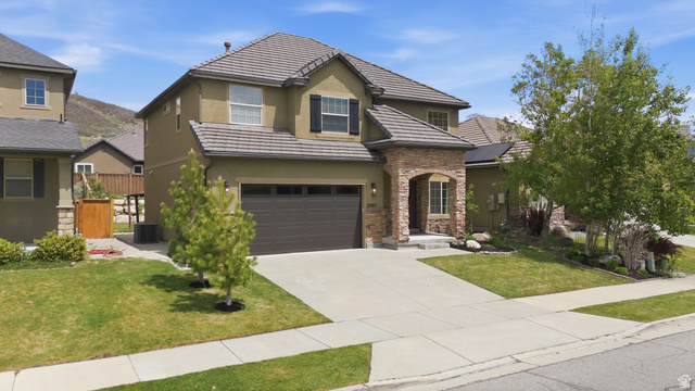 2007 Fielding Hill Lane Draper, UT 84020 - Photo 3 of 83 Two-story residence featuring a tile roof, stucco exterior, stone archway entry, dark-toned garage door, and a concrete driveway