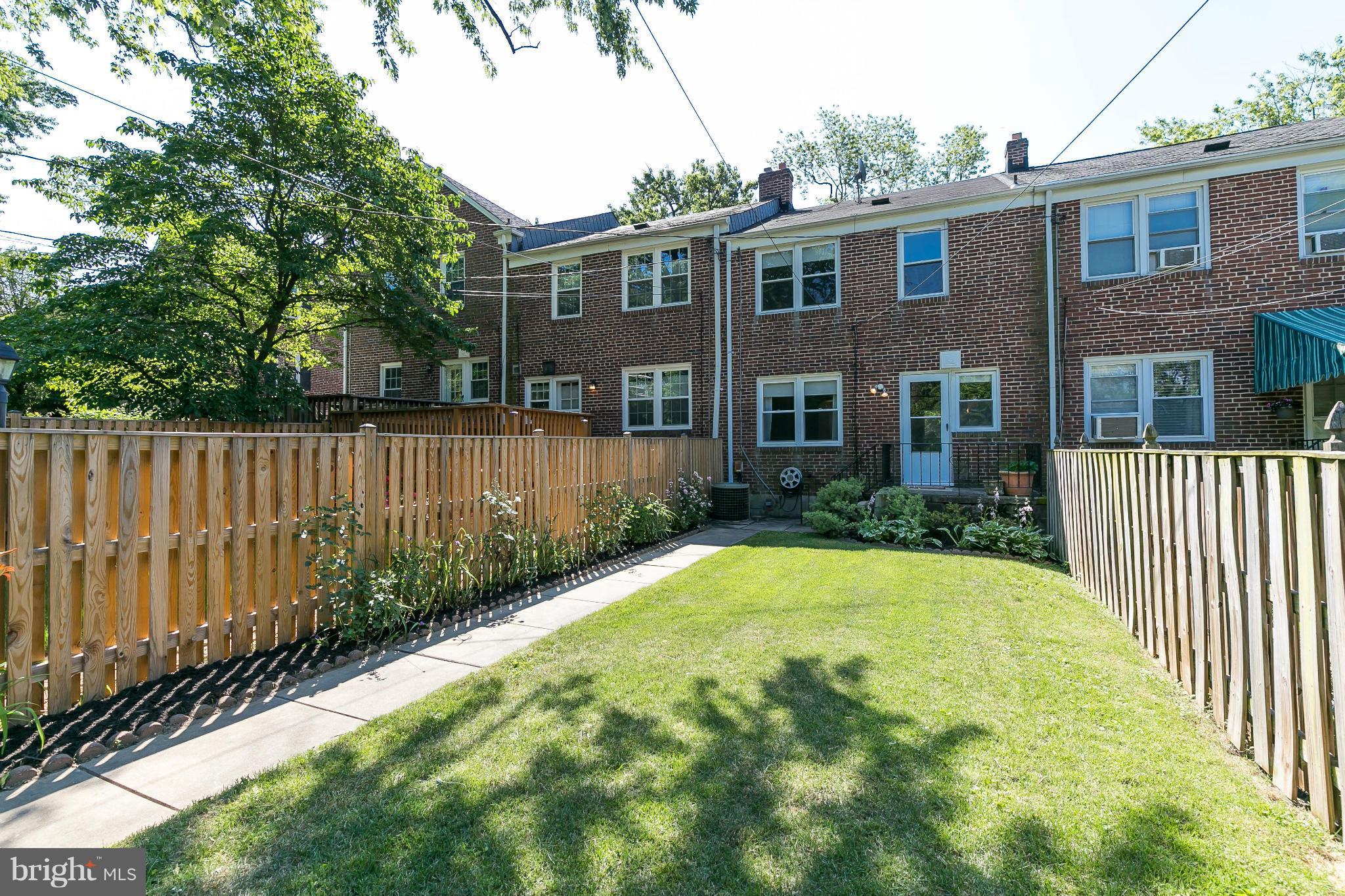 214 Stanmore Road Baltimore, MD 21212 - Photo 19 of 21 a view of a brick house with a small yard plants and a large tree