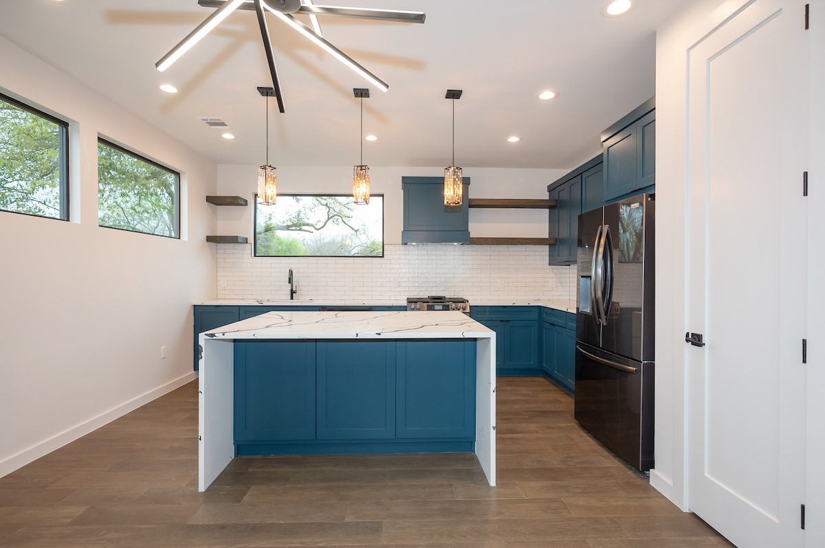 4906 Aberdeen Circle Austin, TX 78745 - Photo 9 of 28 a kitchen with kitchen island stainless steel appliances a sink cabinets and wooden floor