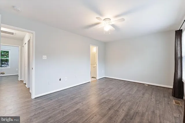 an empty room with wooden floor and ceiling fan