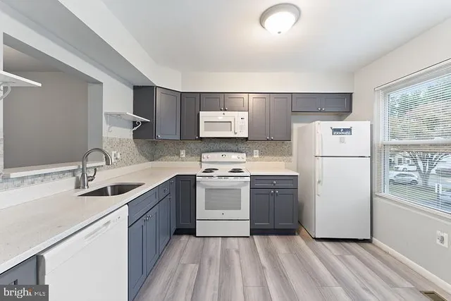 a kitchen with a sink a refrigerator and white cabinets