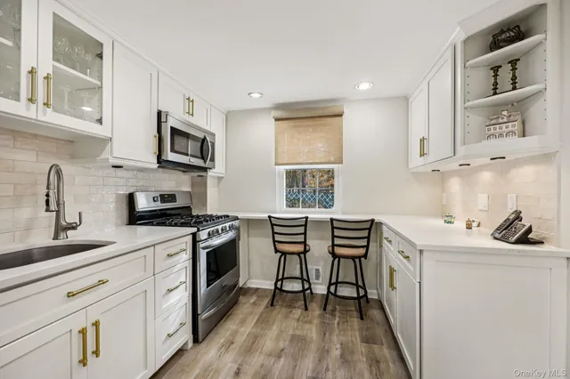 a kitchen with stainless steel appliances a stove a sink a microwave a refrigerator and cabinets