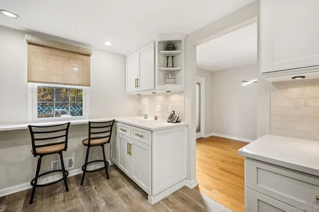 a kitchen with stainless steel appliances kitchen island a table chairs in it and white cabinets