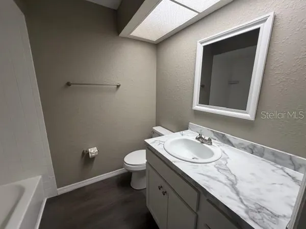 a bathroom with a granite countertop sink toilet and mirror