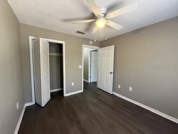 an empty room with wooden floor and fan