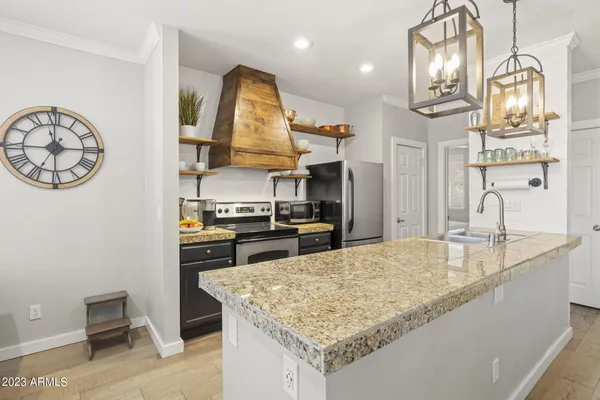 a kitchen with stainless steel appliances granite countertop a sink a stove and a wooden floors