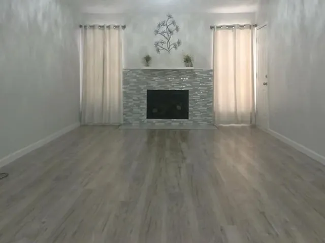 a view of empty room with wooden floor and fireplace
