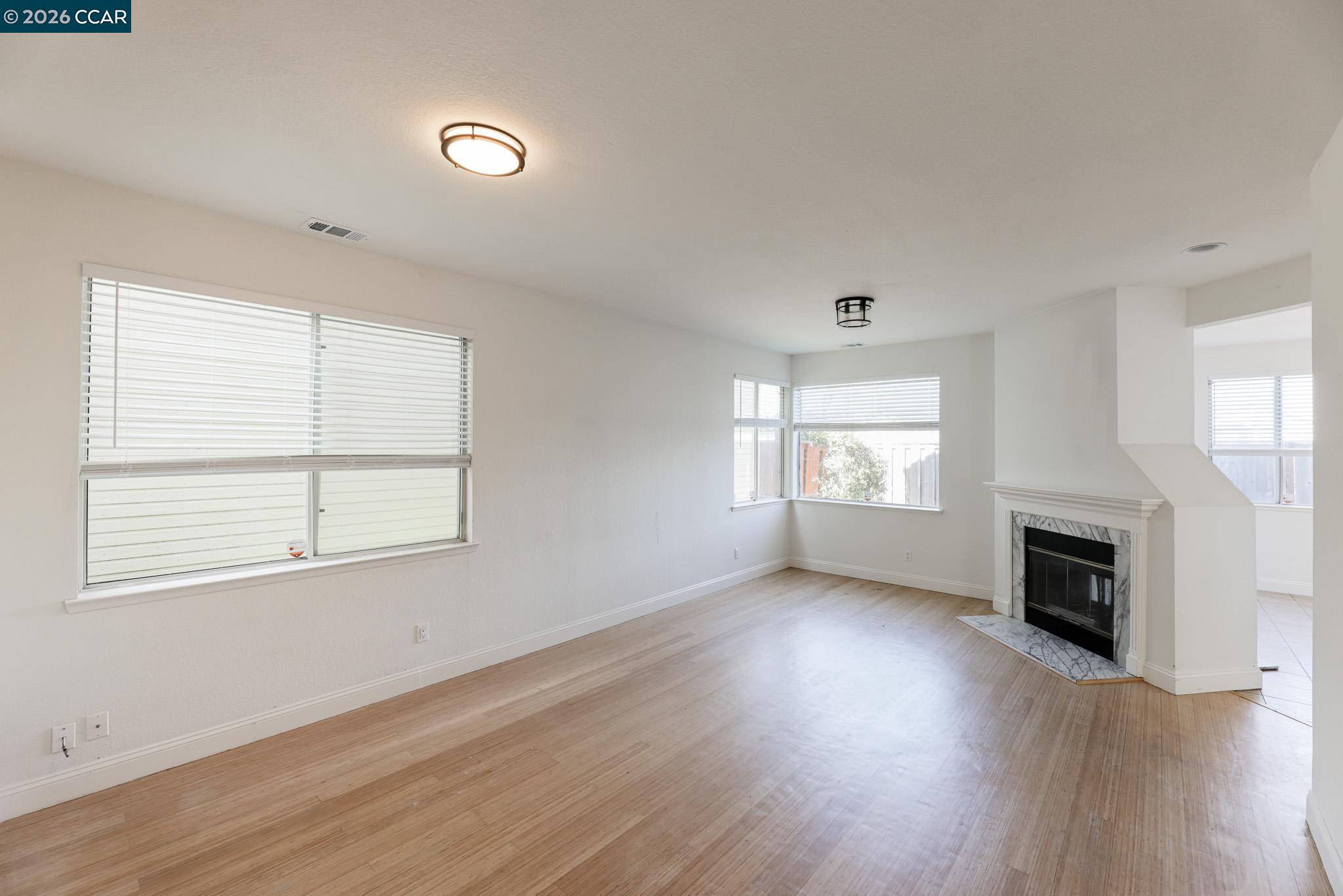 528 Dohrmann Lane Pinole, CA 94564 - Photo 4 of 27 an empty room with wooden floor fireplace and windows