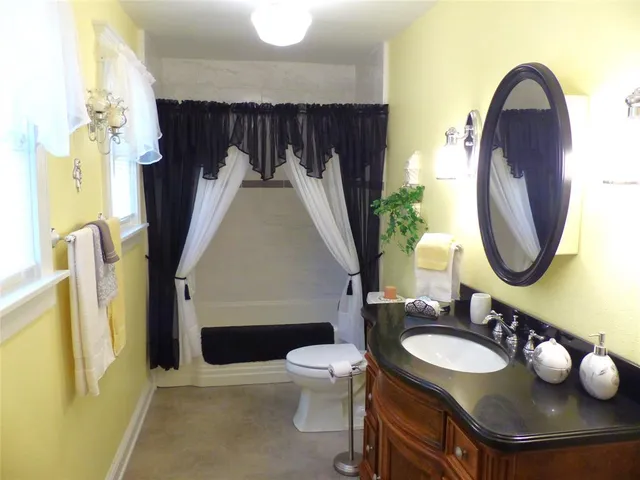 a bathroom with a toilet sink vanity granite and a mirror