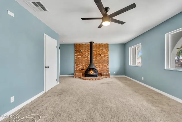 an empty room with windows and ceiling fan