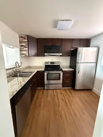a kitchen with granite countertop a refrigerator a sink a stove and oven