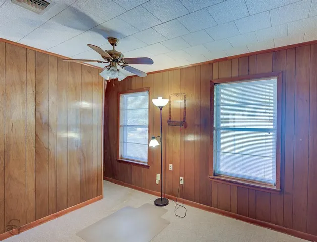 an empty room with windows and fan