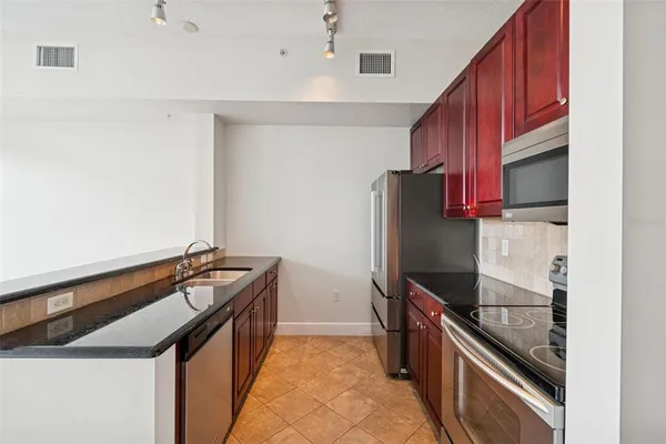 a kitchen with granite countertop a stove refrigerator and microwave