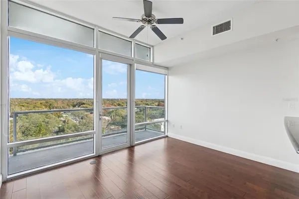an empty room with wooden floor fan and windows