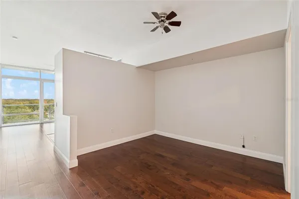 a view of empty room with wooden floor and fan