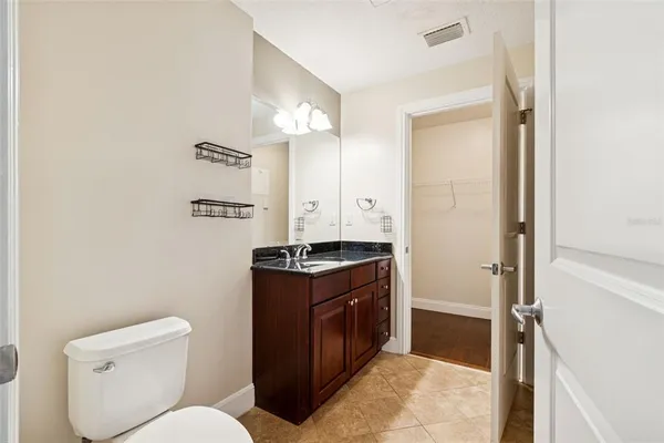 a spacious bathroom with a granite countertop toilet a sink and a mirror