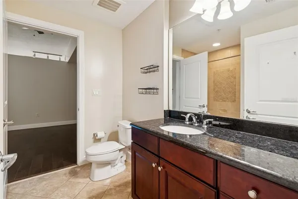 a bathroom with a granite countertop sink a toilet and a large mirror