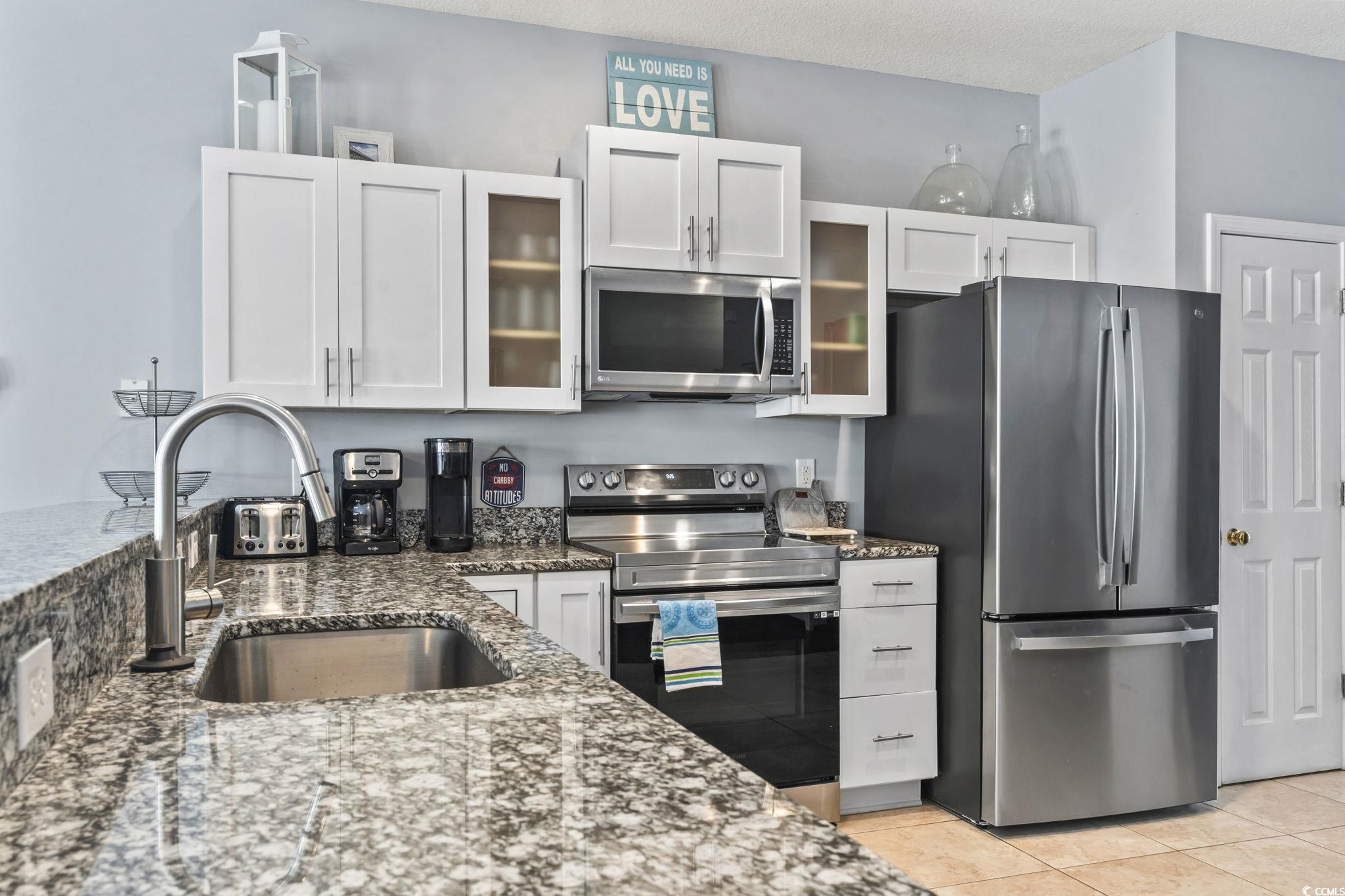 105 B Woodland Drive Murrells Inlet, SC 29576 - Photo 3 of 21 Kitchen with appliances with stainless steel finishes, dark stone countertops, white cabinetry, glass insert cabinets, and a textured ceiling