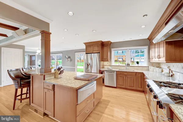 a kitchen with stainless steel appliances granite countertop a stove a refrigerator a sink a dining table and chairs with wooden floor