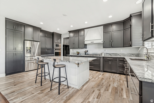 1526 South 500 West Mapleton, UT 84664 - Photo 3 of 54 Dual tone kitchen featuring a breakfast bar area, light stone counters, stainless steel appliances, light wood-style floors, and a center island