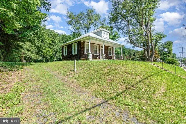 a house is sitting in middle of green field
