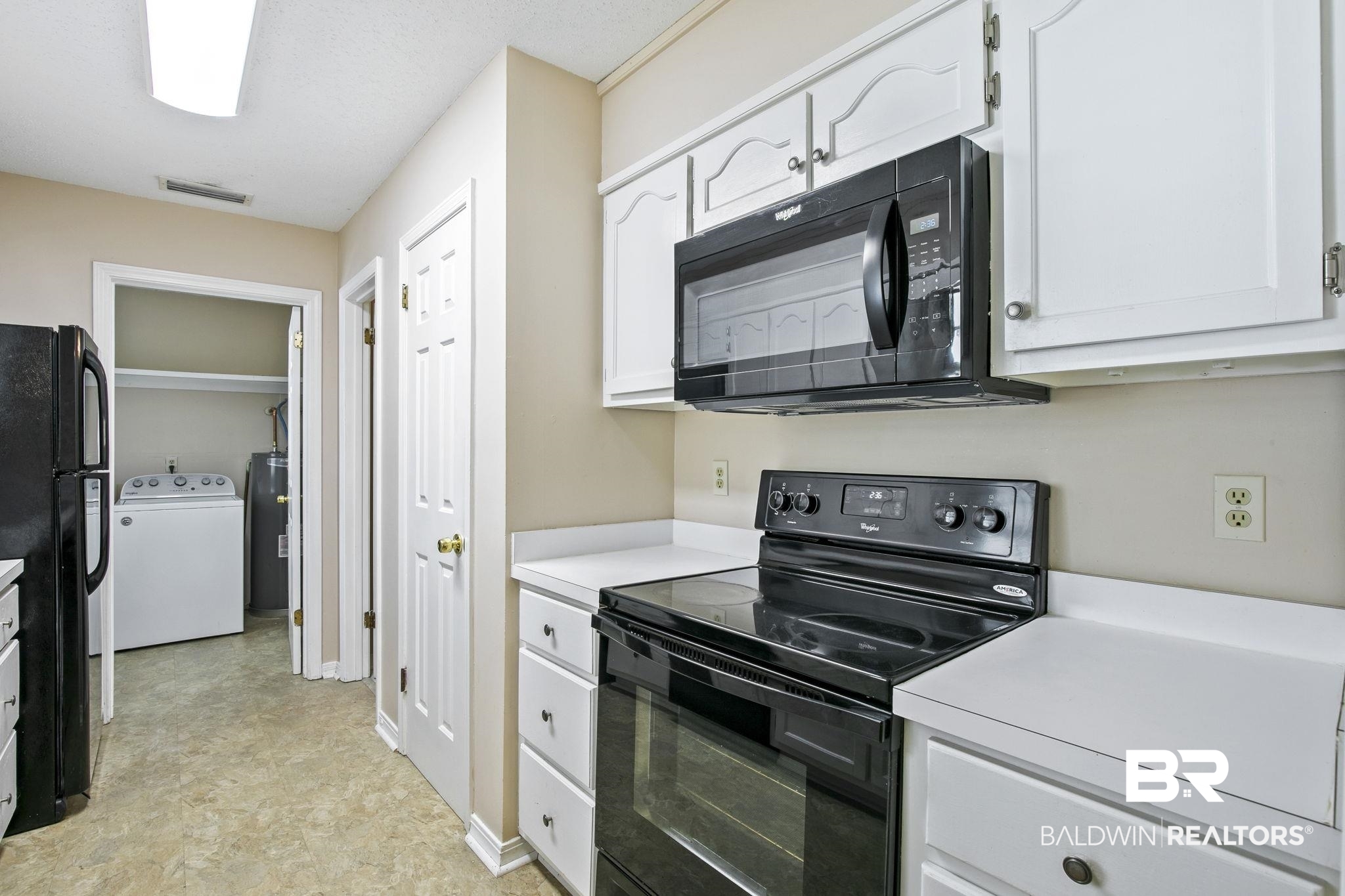 359 Ridgewood Drive Daphne, AL 36526 - Photo 21 of 73 Kitchen featuring washer / dryer, black appliances, white cabinets, and gas water heater