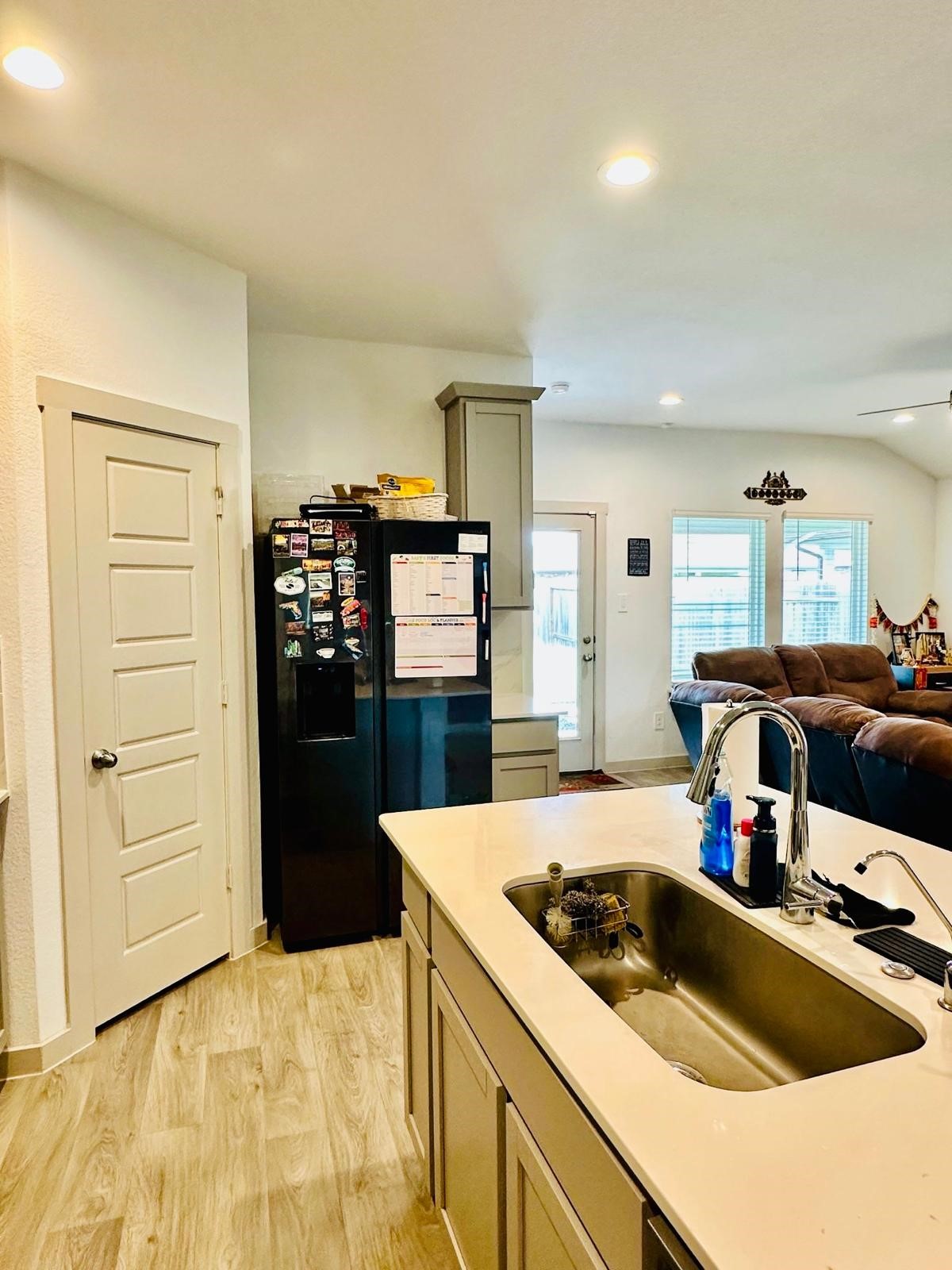 315 John House Lane Rosharon, TX 77583 - Photo 16 of 27 Modern kitchen with sleek light wood cabinets, a spacious island with a sink, and stainless steel appliances. The room features ample counter space, recessed lighting, and a stylish backsplash, creating a bright and inviting space for cooking and entertaining.