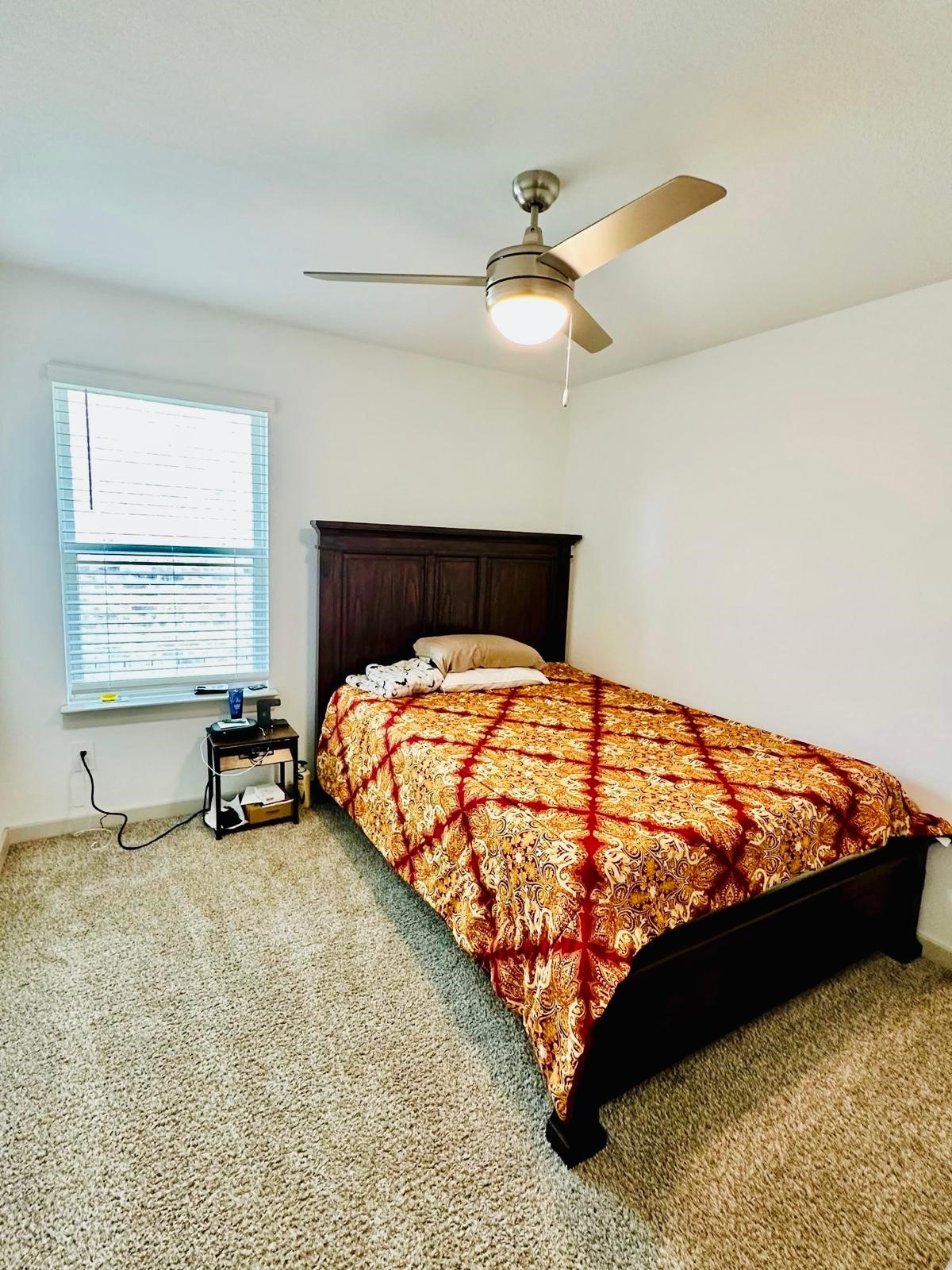 315 John House Lane Rosharon, TX 77583 - Photo 21 of 27 This cozy bedroom features a comfortable bed with a decorative cover, a ceiling fan for airflow, plush carpet, and a window providing natural light. Ideal for relaxation.