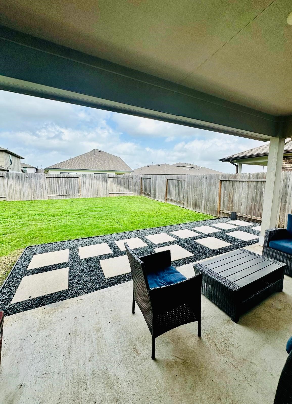 315 John House Lane Rosharon, TX 77583 - Photo 25 of 27 Spacious backyard featuring a well-maintained lawn, bordered by a wooden fence for privacy. A modern stone pathway adds style and functionality, perfect for outdoor activities or gatherings.