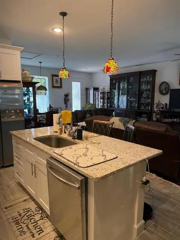 a kitchen that has a sink a stove and a dining table with white countertops