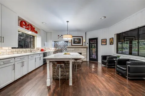 a kitchen with stainless steel appliances a dining table chairs and wooden floor